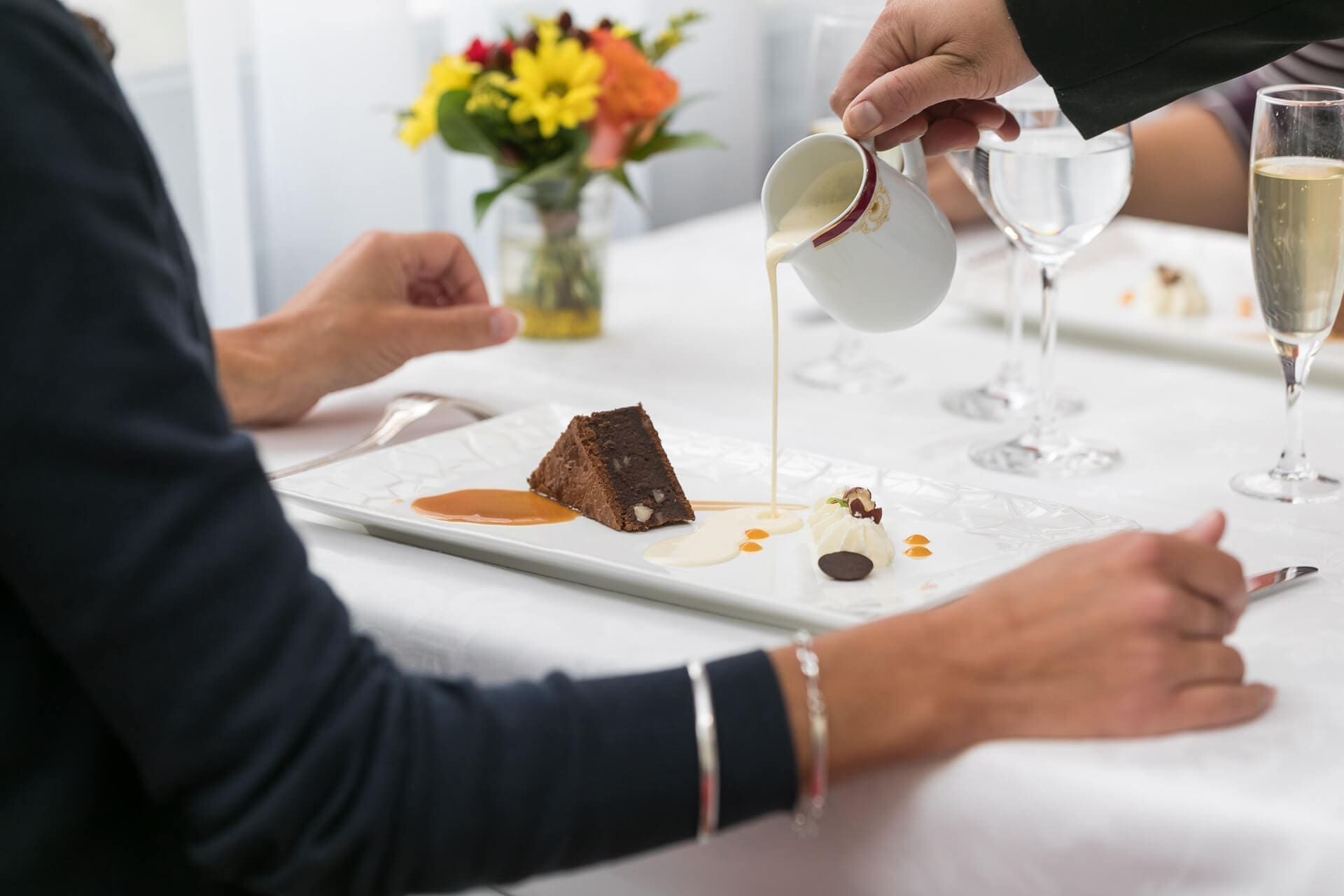 Serveur versant un coulis sur un dessert au sein du restaurant Villa Médicis