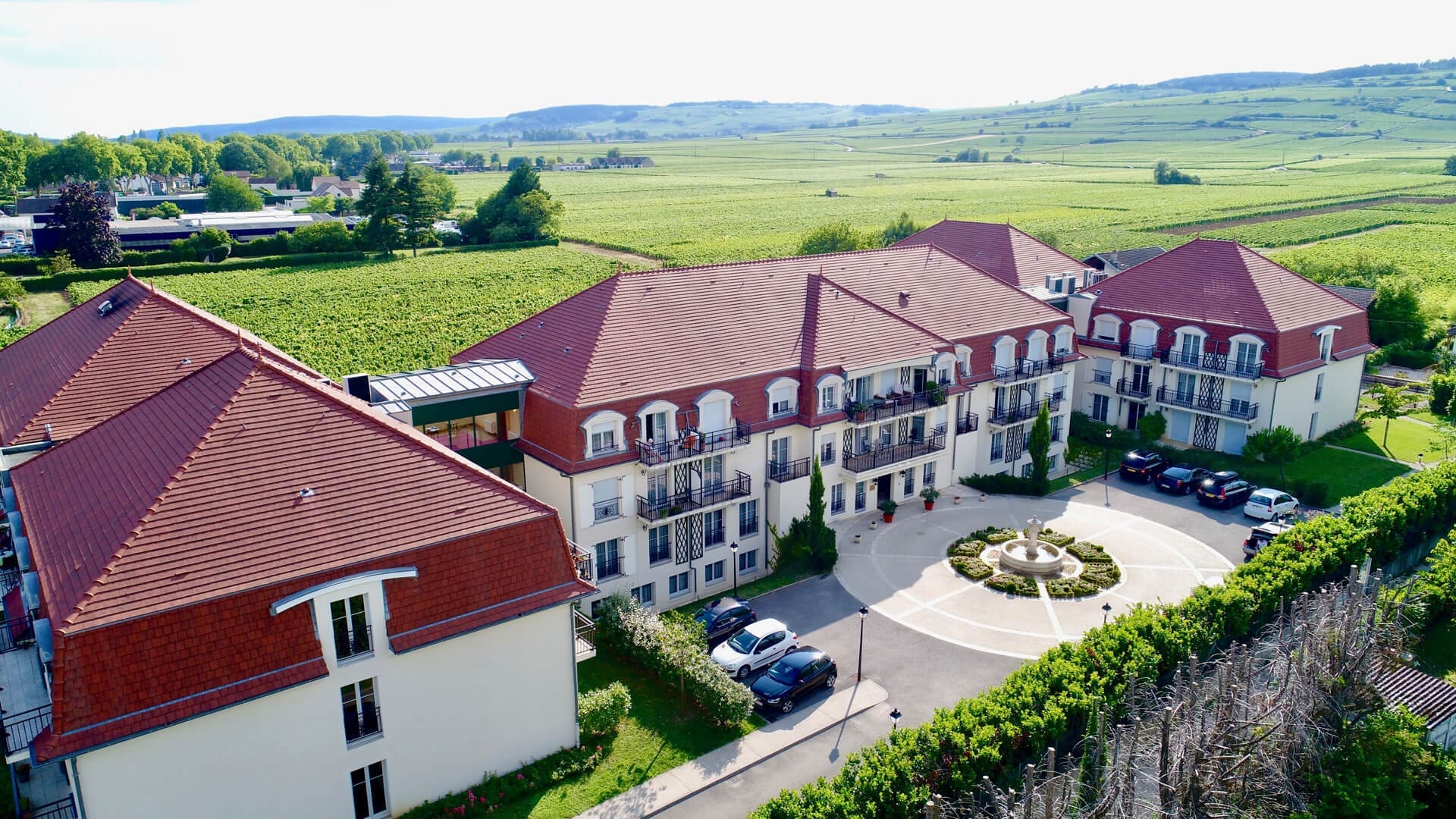 Vue aérienne Résidences senior Beaune avec fontaine et paysage v